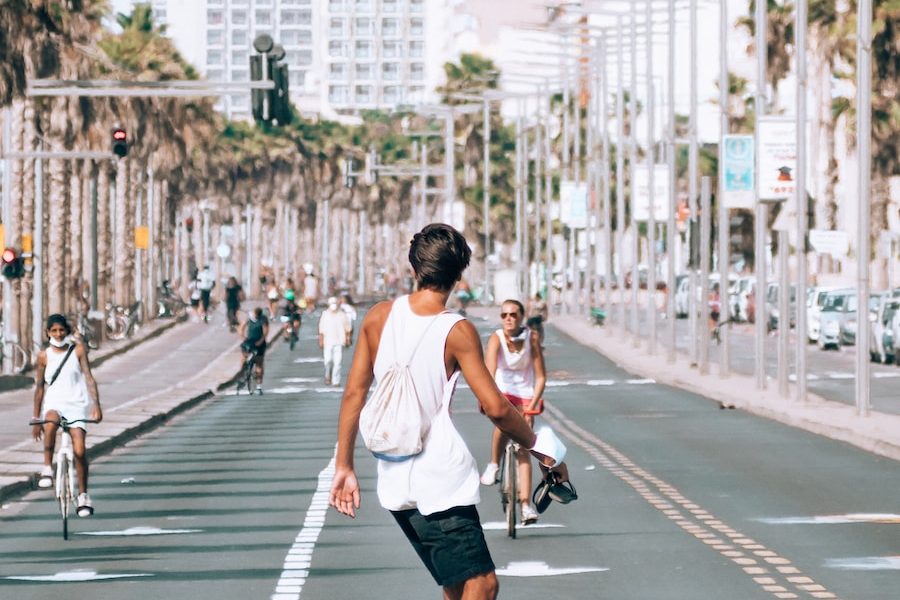 tel aviv man in white tank top and black shorts running on pedestrian lane during daytime